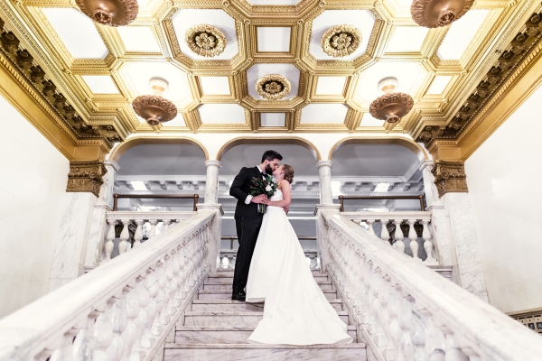 Romantic wedding photo of bride and groom kissing on marble staircase at Chicago Athletic Association Hotel