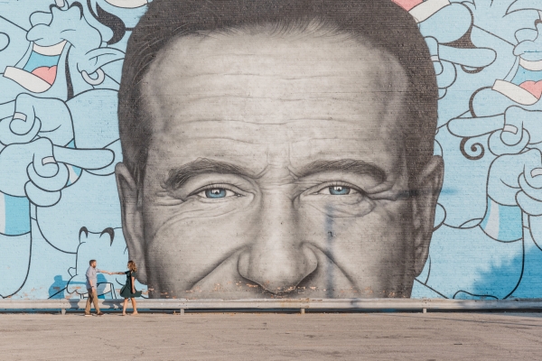 Couple dancing in front of Robin Williams mural