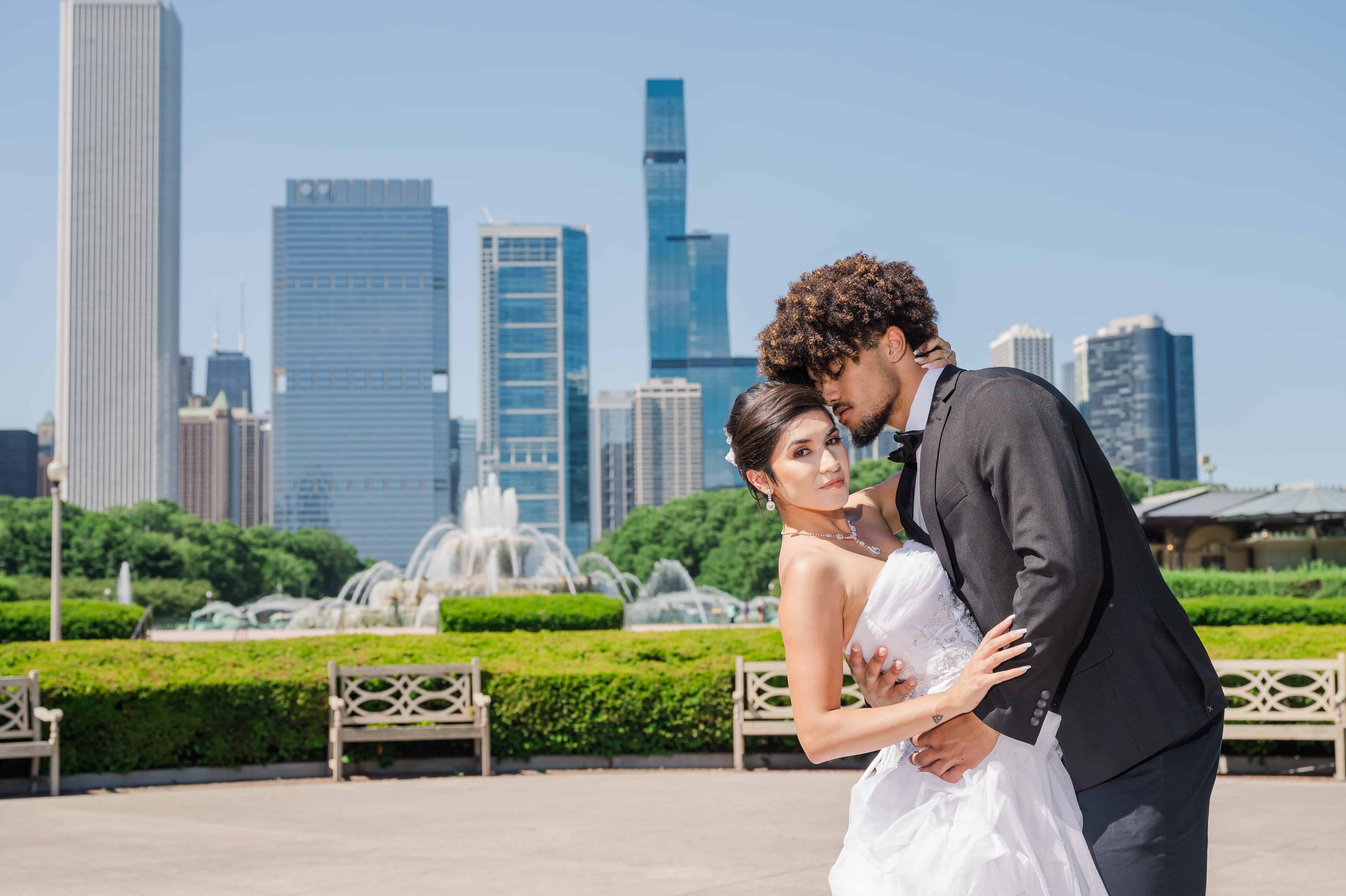 Wedding couple portrait in front of Buckingham fountain and downtown Chicago on a clear summer day.