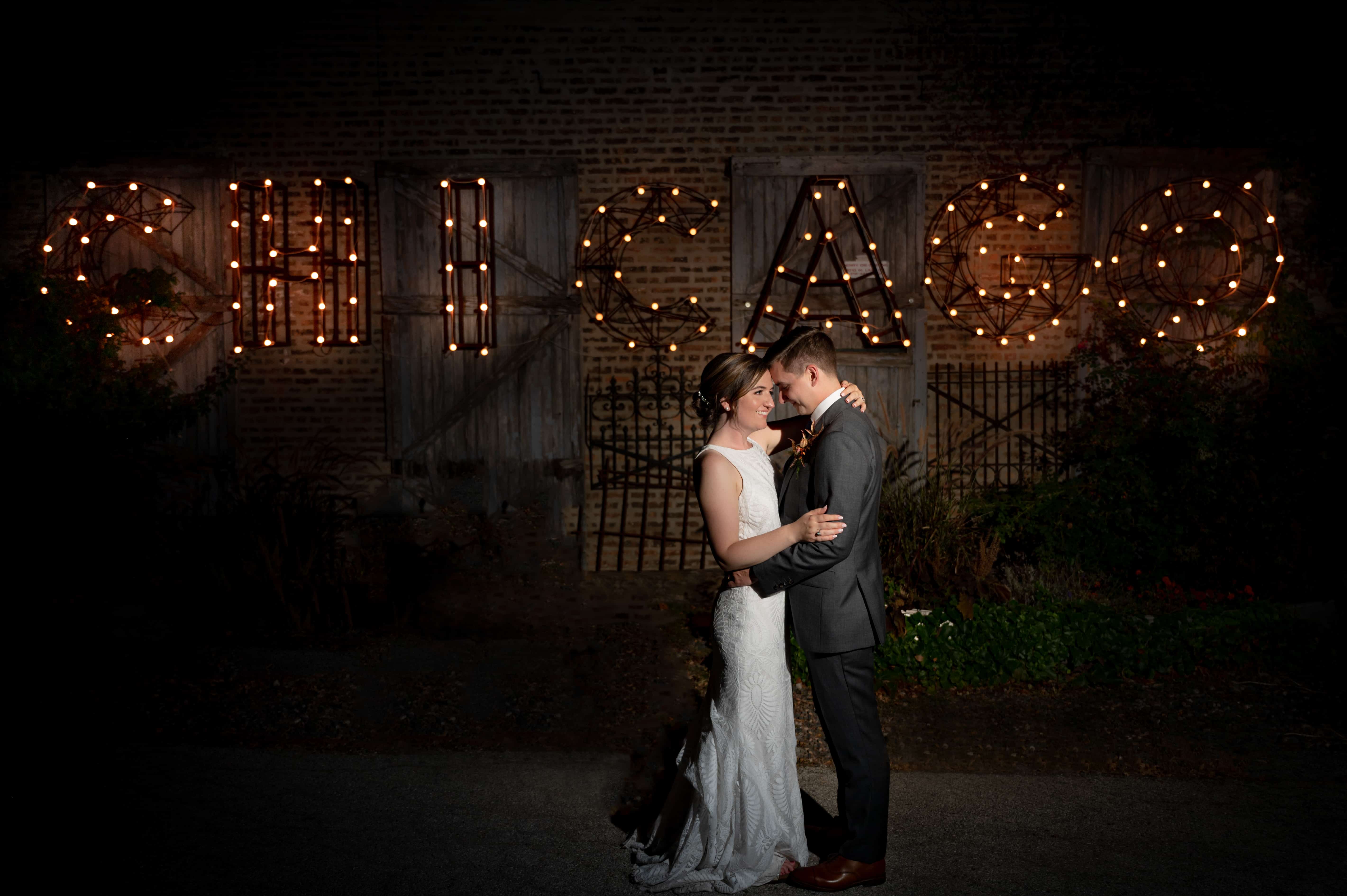 Night portrait of Bride and Groom standing in front of Chicago sign at Salvage One