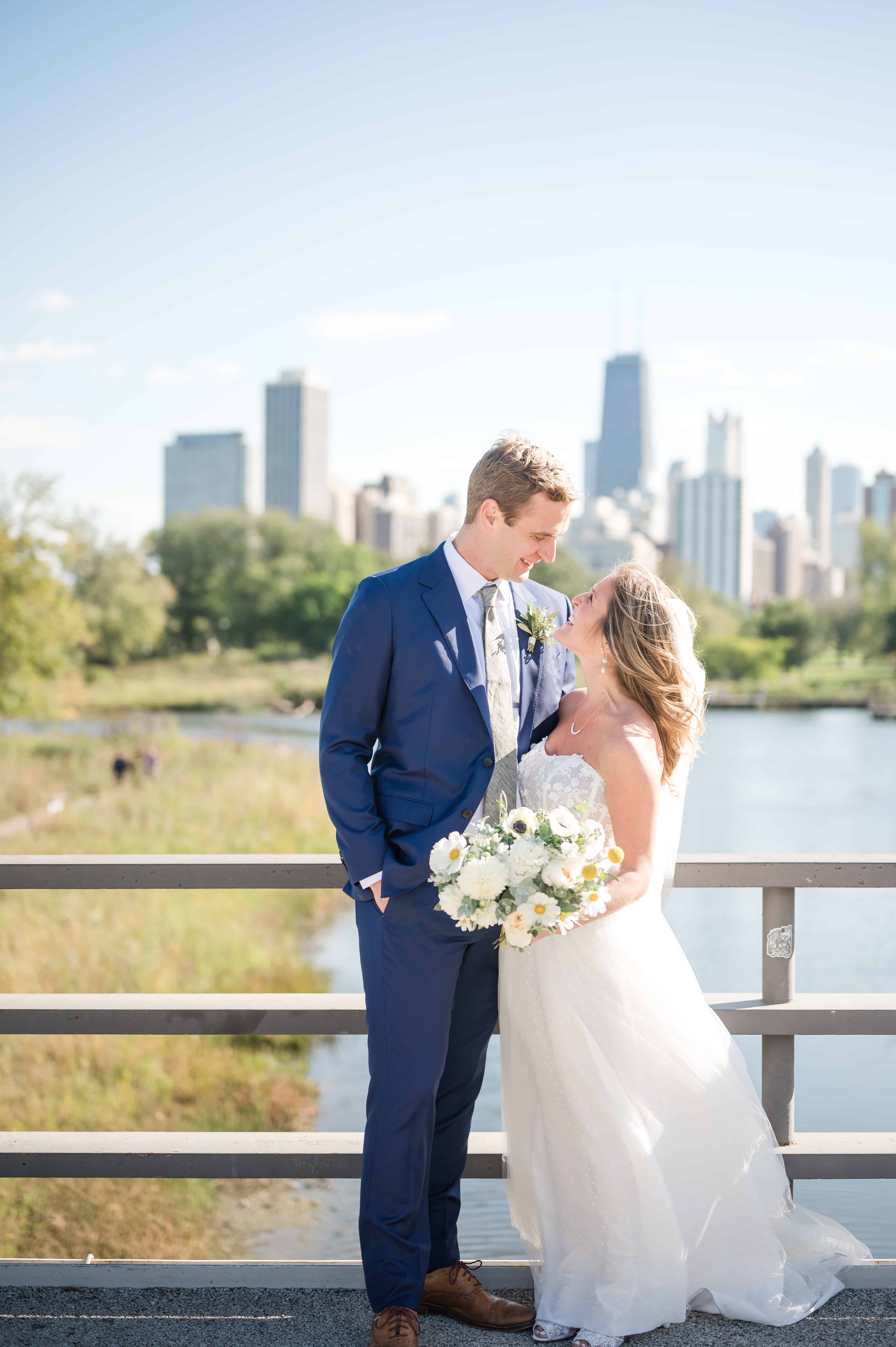 Wedding couple standing on bridge at Lincoln Park Zoo overlooking downtown Chicago