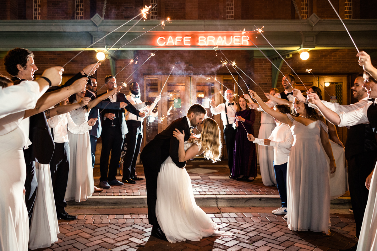 Romantic photo of bride and groom kissing outside Cafe Brauer wedding venue during sparkler exit