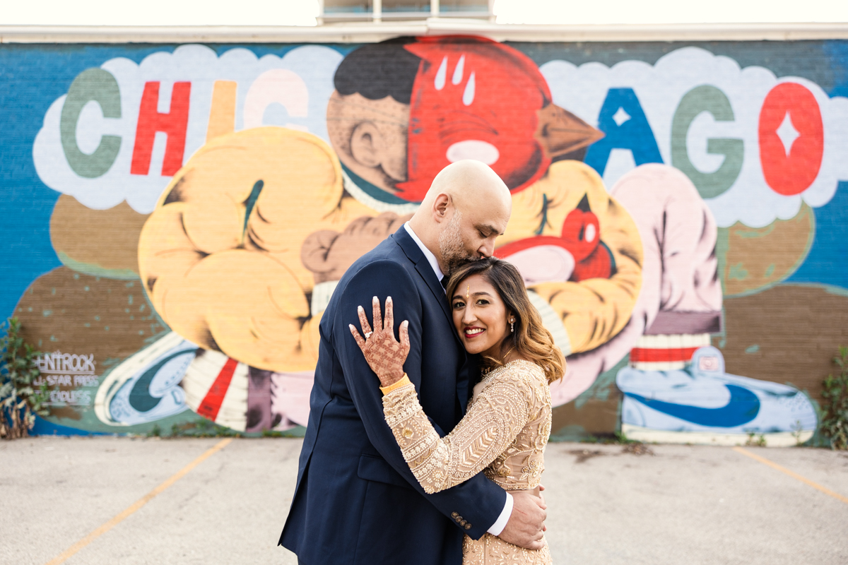 Bride and groom embrace in front of colorful Chicago mural during their West Loop wedding reception